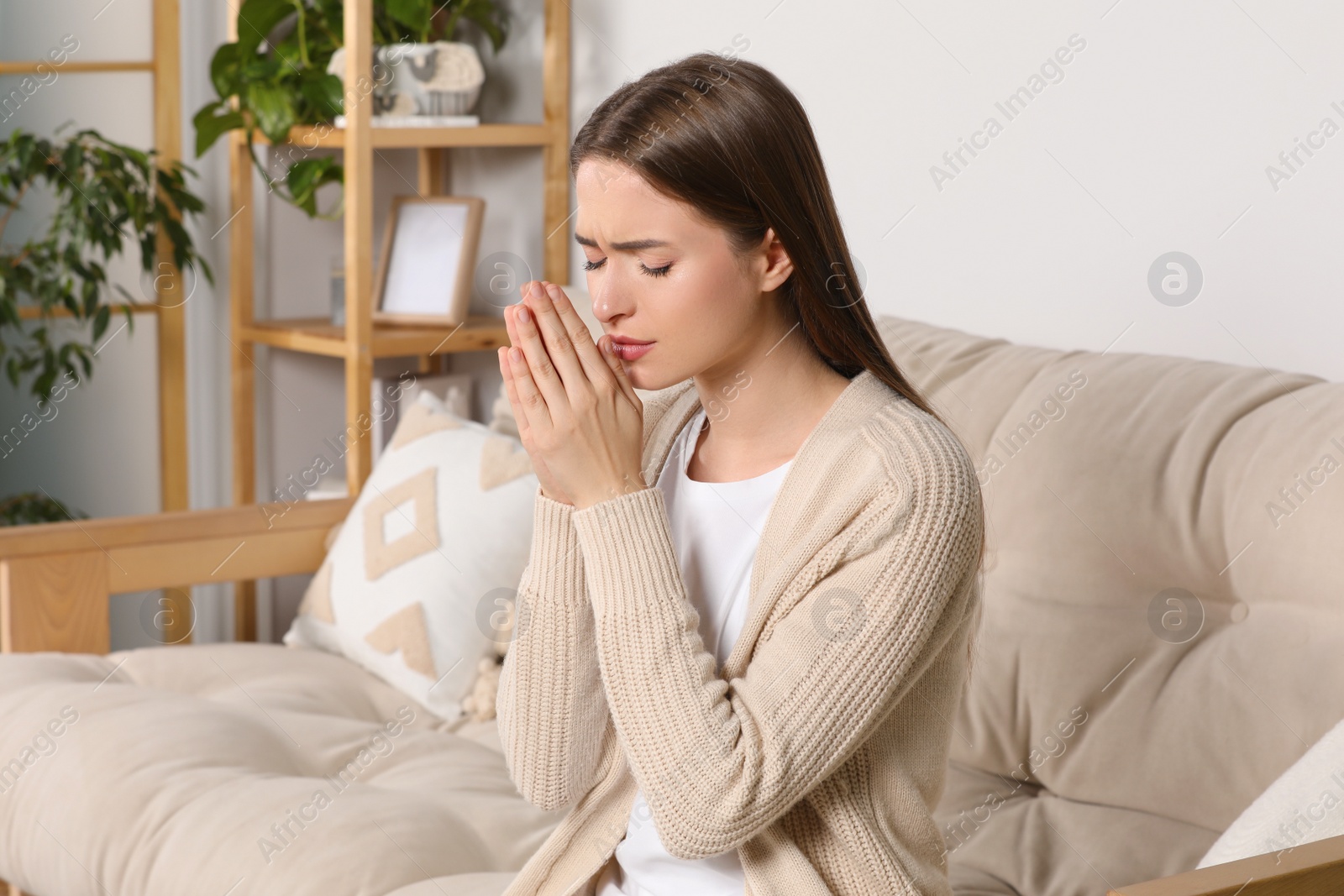 Photo of Woman with clasped hands praying at home