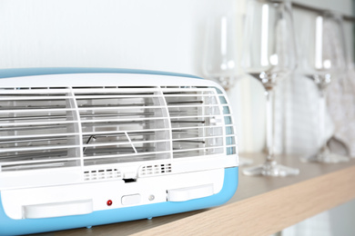 Modern air purifier on wooden shelf, closeup