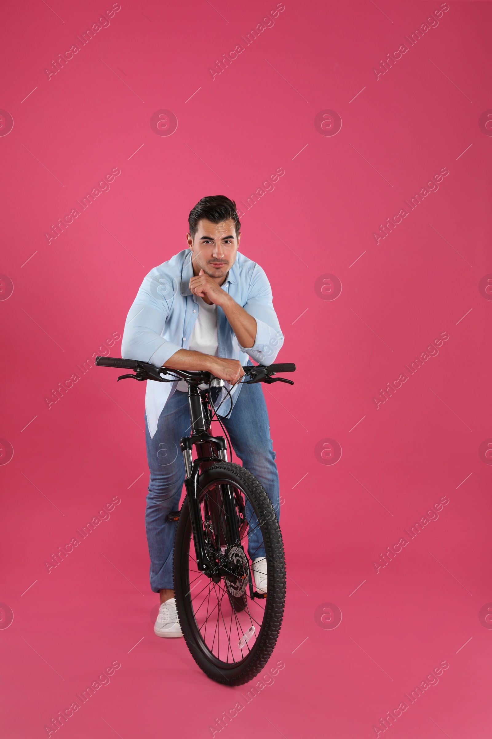 Photo of Handsome young man with modern bicycle on pink background