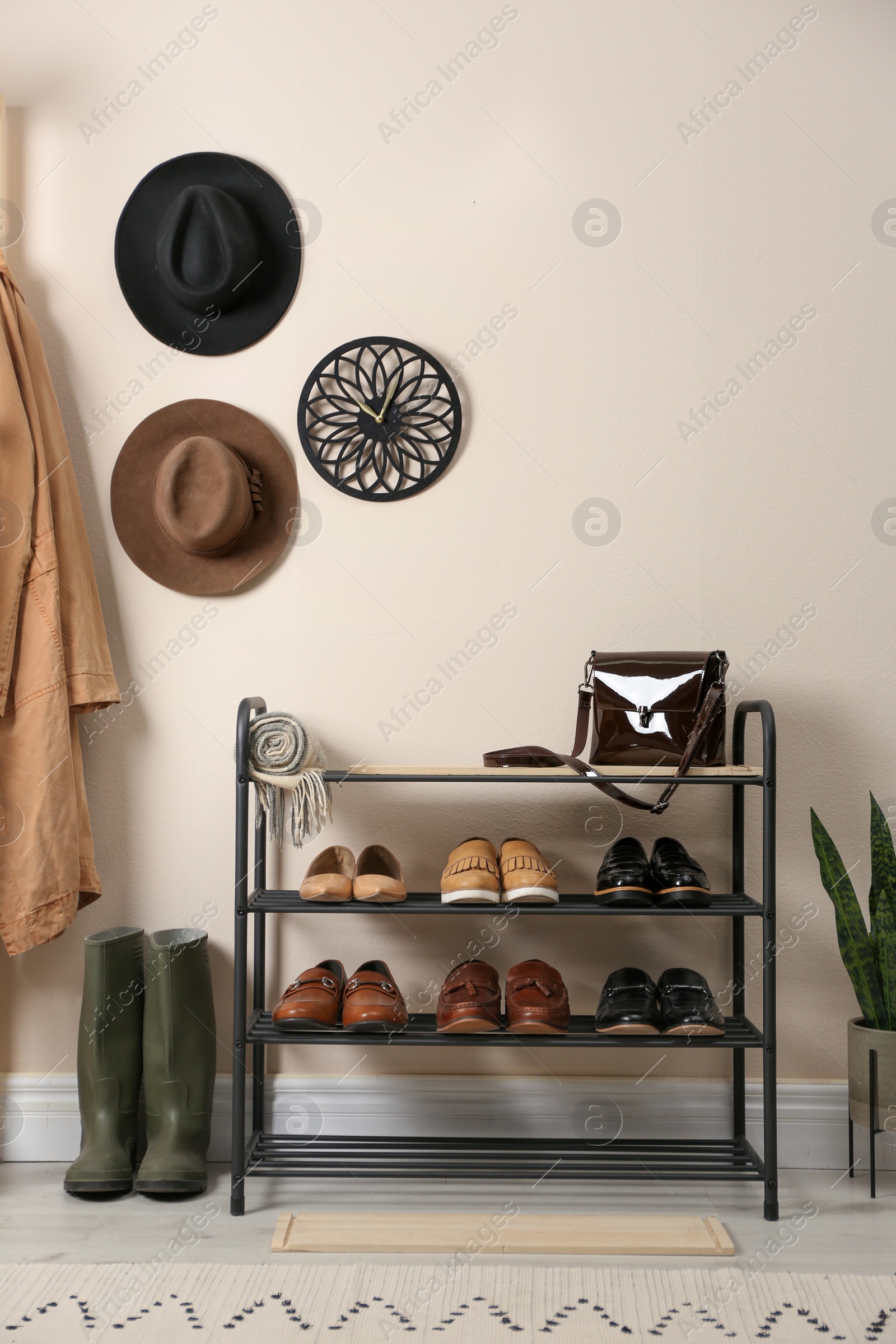 Photo of Rack with different shoes near beige wall in room