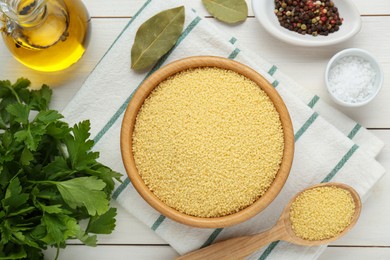 Raw couscous and ingredients on white wooden table, flat lay