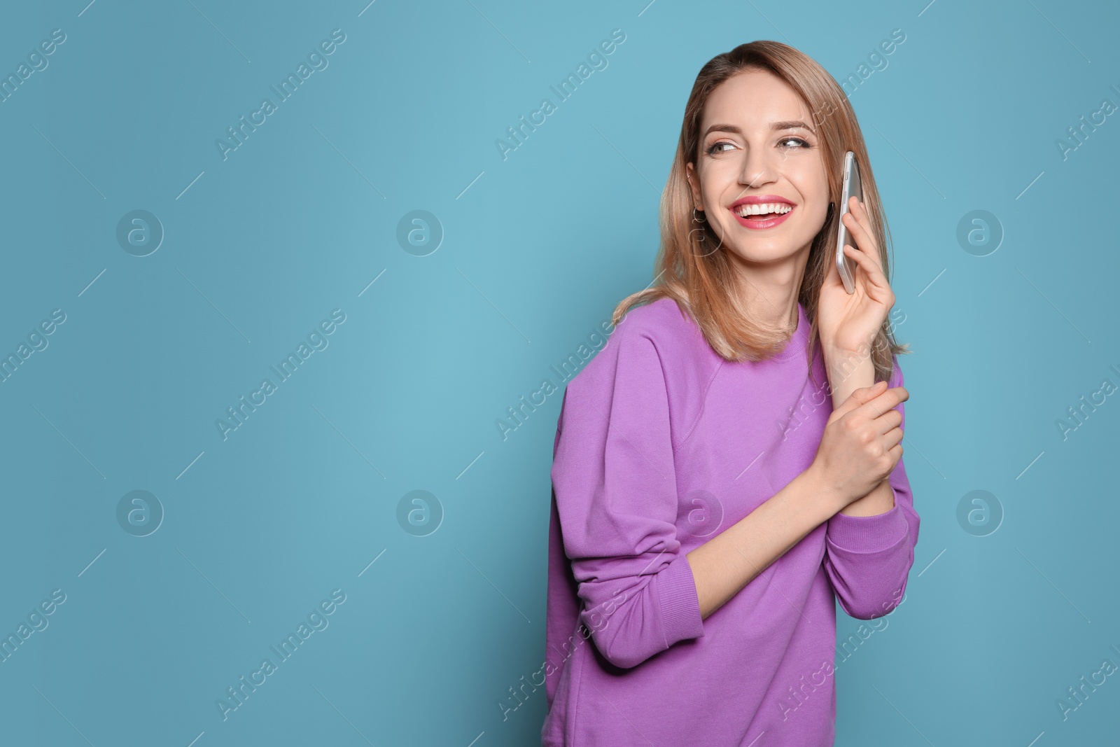 Photo of Young woman talking on phone against color background