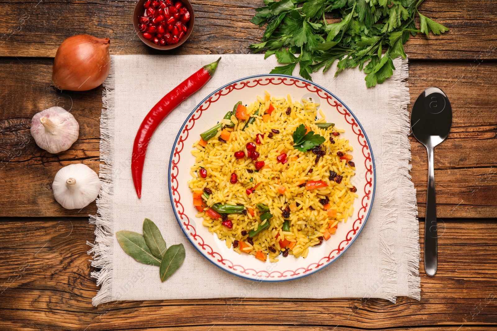 Photo of Tasty rice pilaf with vegetables served on wooden table, flat lay