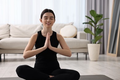 Photo of Beautiful girl meditating on yoga mat at home