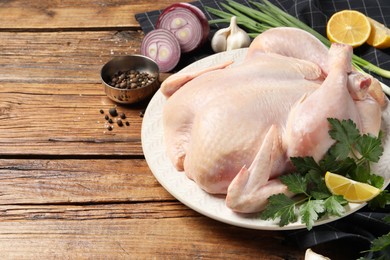 Fresh raw chicken with different products on wooden table, space for text