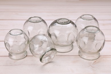 Photo of Glass cups on white wooden table. Cupping therapy