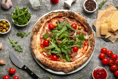 Photo of Tasty pizza with meat and arugula on grey table, flat lay