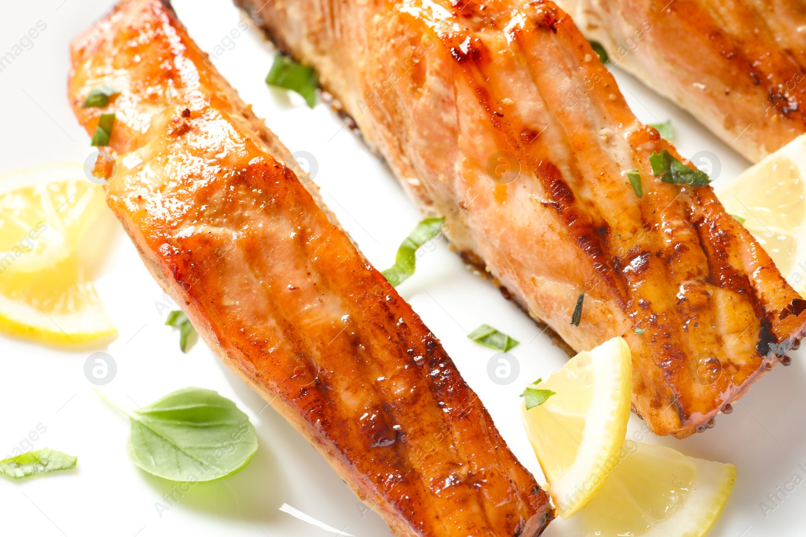 Photo of Tasty freshly cooked salmon with lemon and basil, closeup