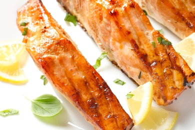 Photo of Tasty freshly cooked salmon with lemon and basil, closeup