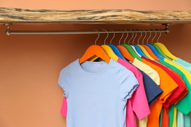 Photo of Rack with different child's clothes near coral wall, closeup