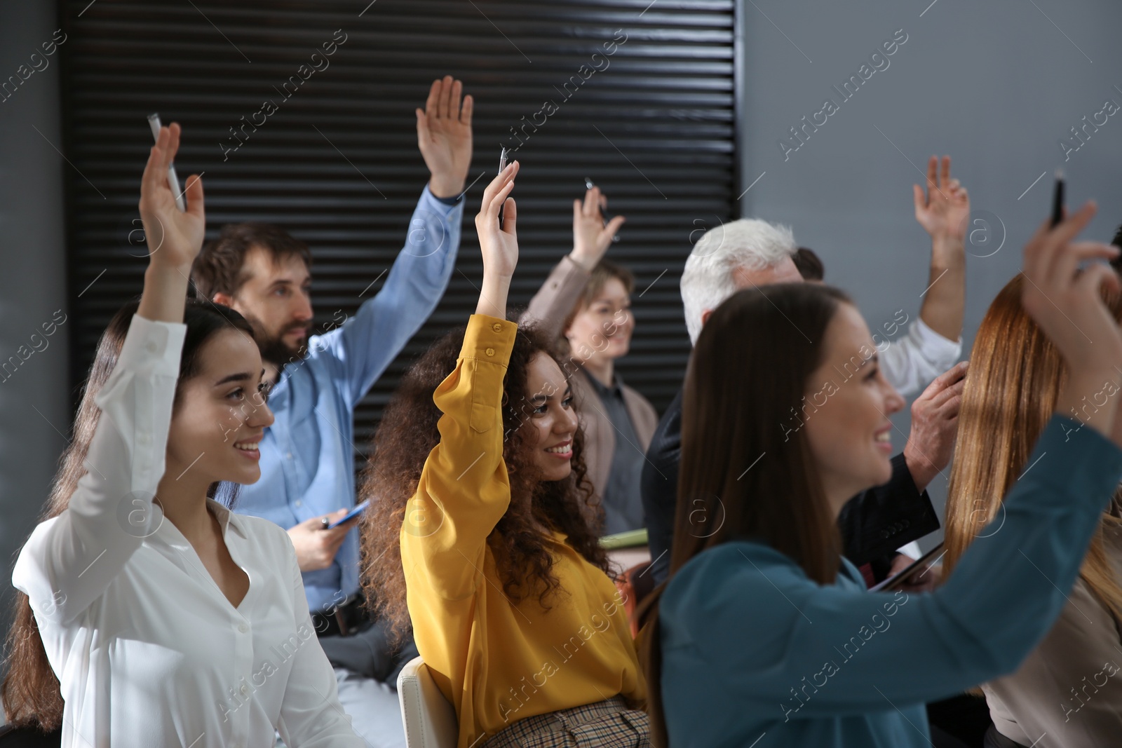 Photo of People raising hands to ask questions at seminar in office