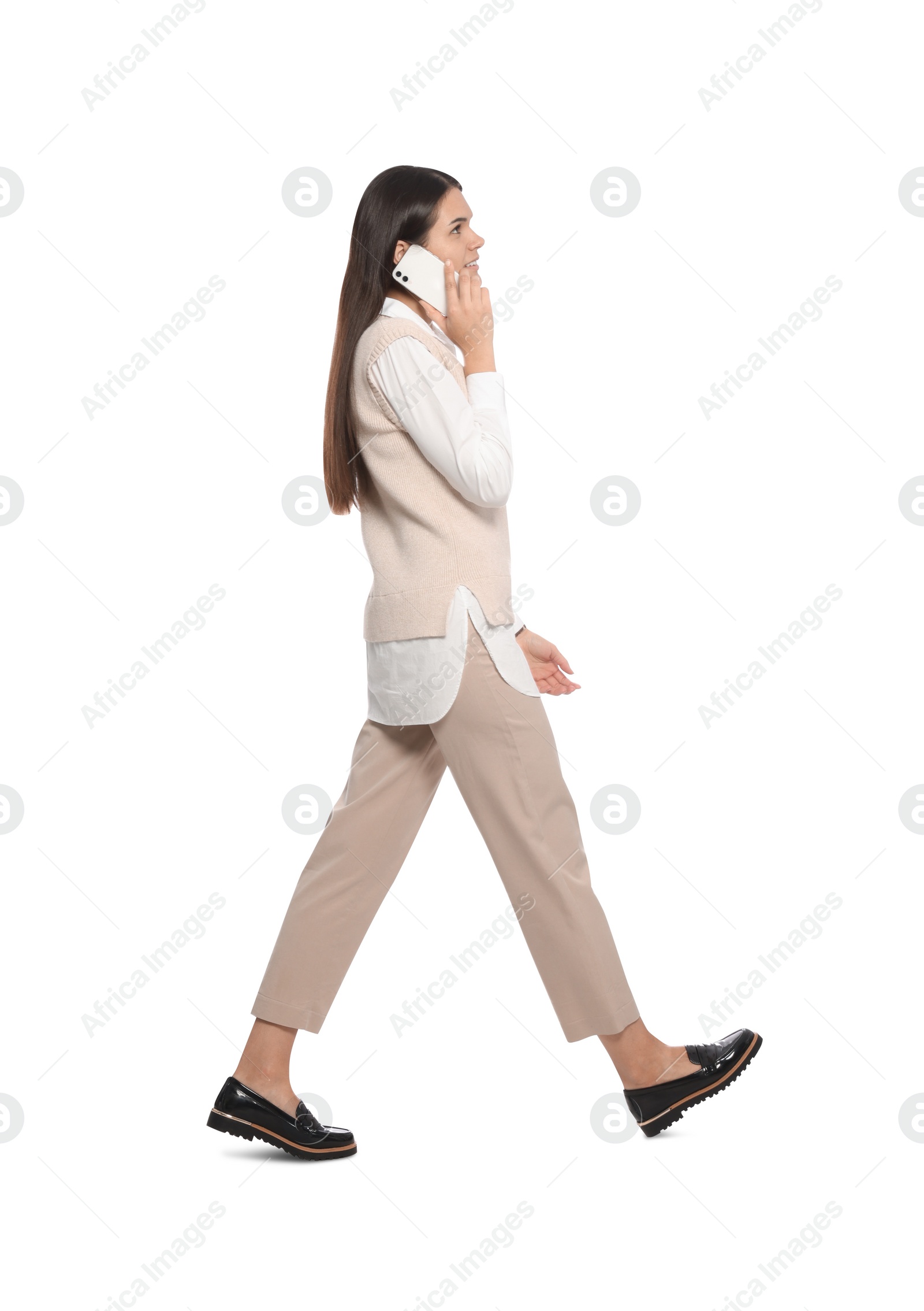 Photo of Young woman talking on phone while walking against white background