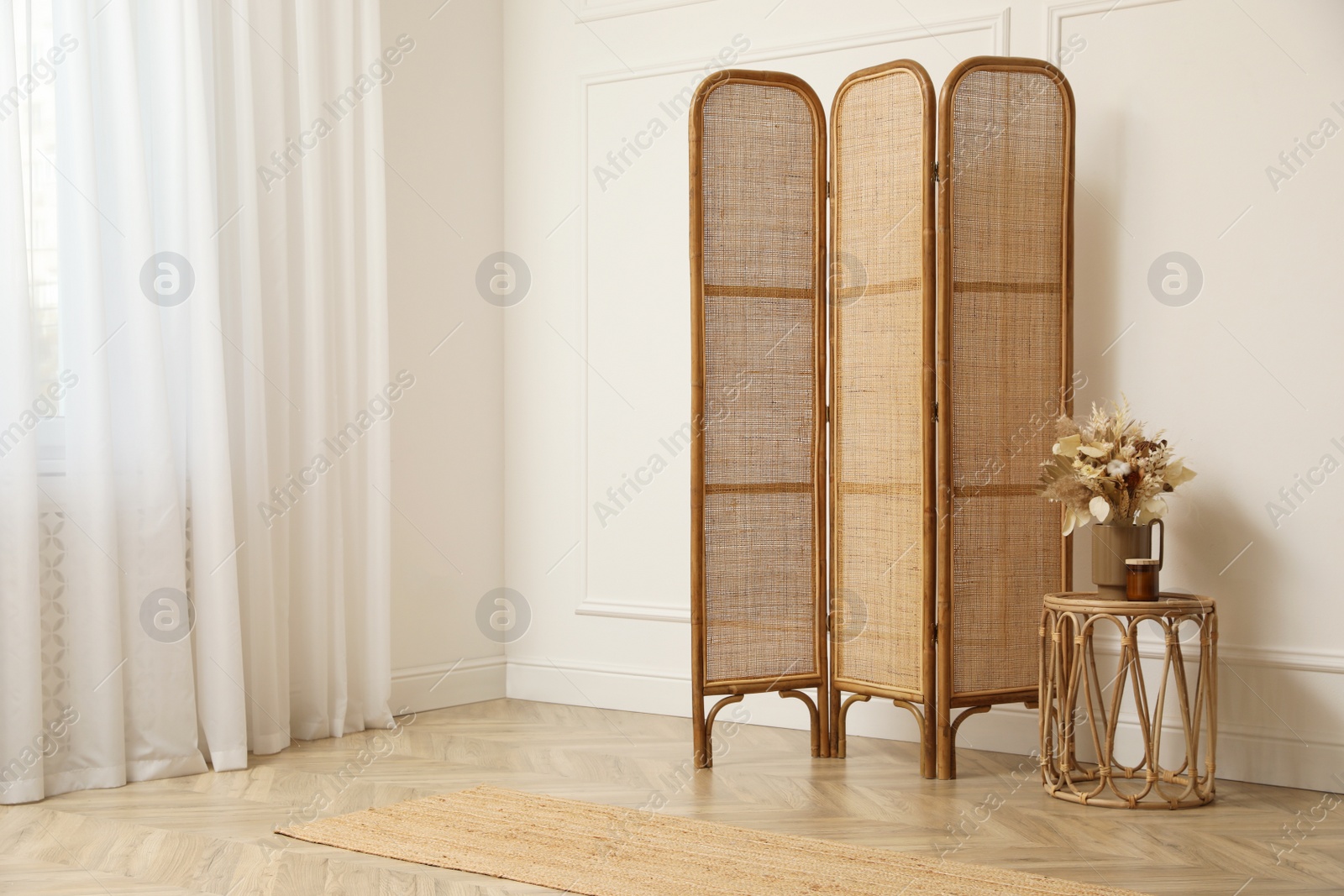 Photo of Folding screen and small table with flowers in room. Interior design