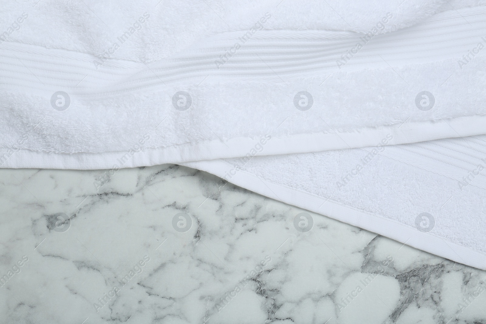 Photo of Terry towel on white marble table, top view. Space for text