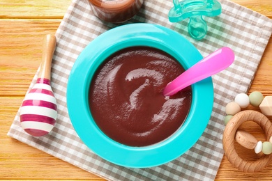 Photo of Flat lay composition with bowl of healthy baby food on wooden table