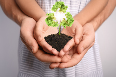 Image of Family holding fertile soil in hands together and recycling symbol, closeup 