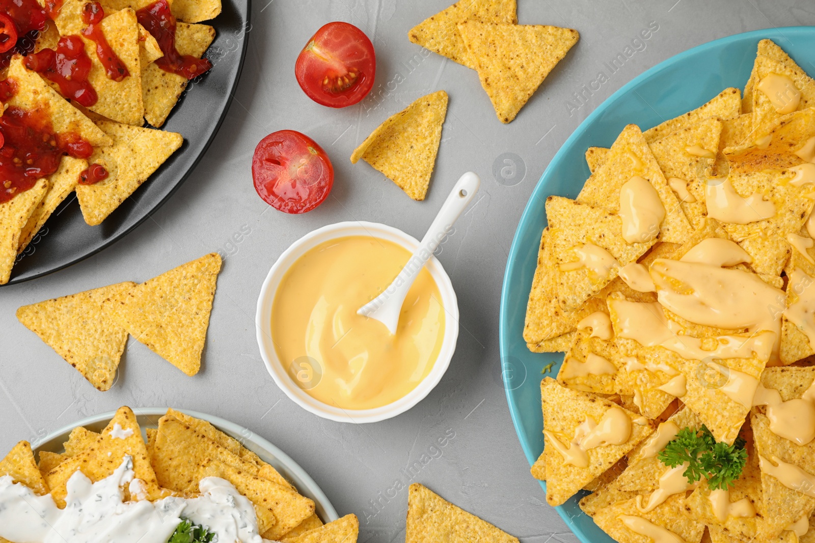 Photo of Mexican nacho chips with different sauces on grey table, flat lay