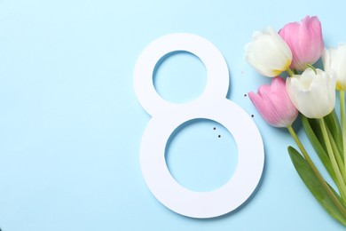 Photo of 8th of March greeting card design with paper number eight, beautiful flowers and space for text on light blue background, flat lay. International Women's day