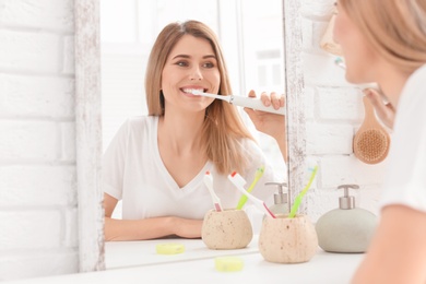 Photo of Young woman brushing her teeth in bathroom
