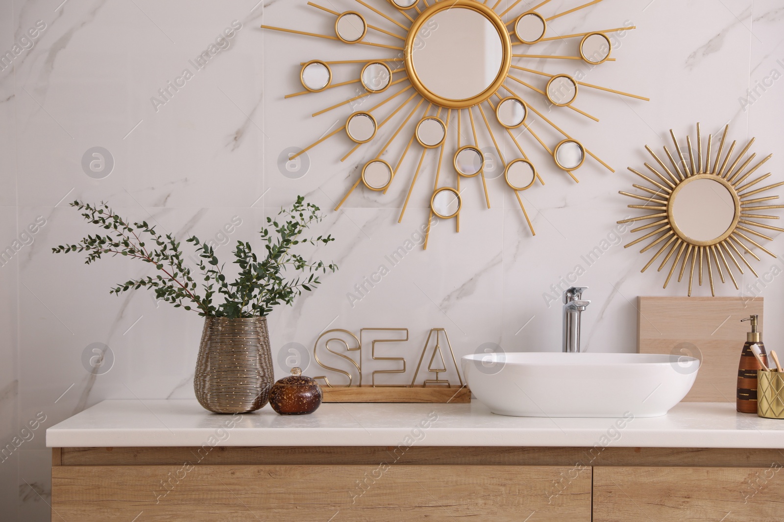 Photo of Vase with beautiful branches and toiletries near vessel sink in bathroom. Interior design