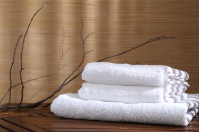 Stacked soft towels on wooden table and tree branches indoors