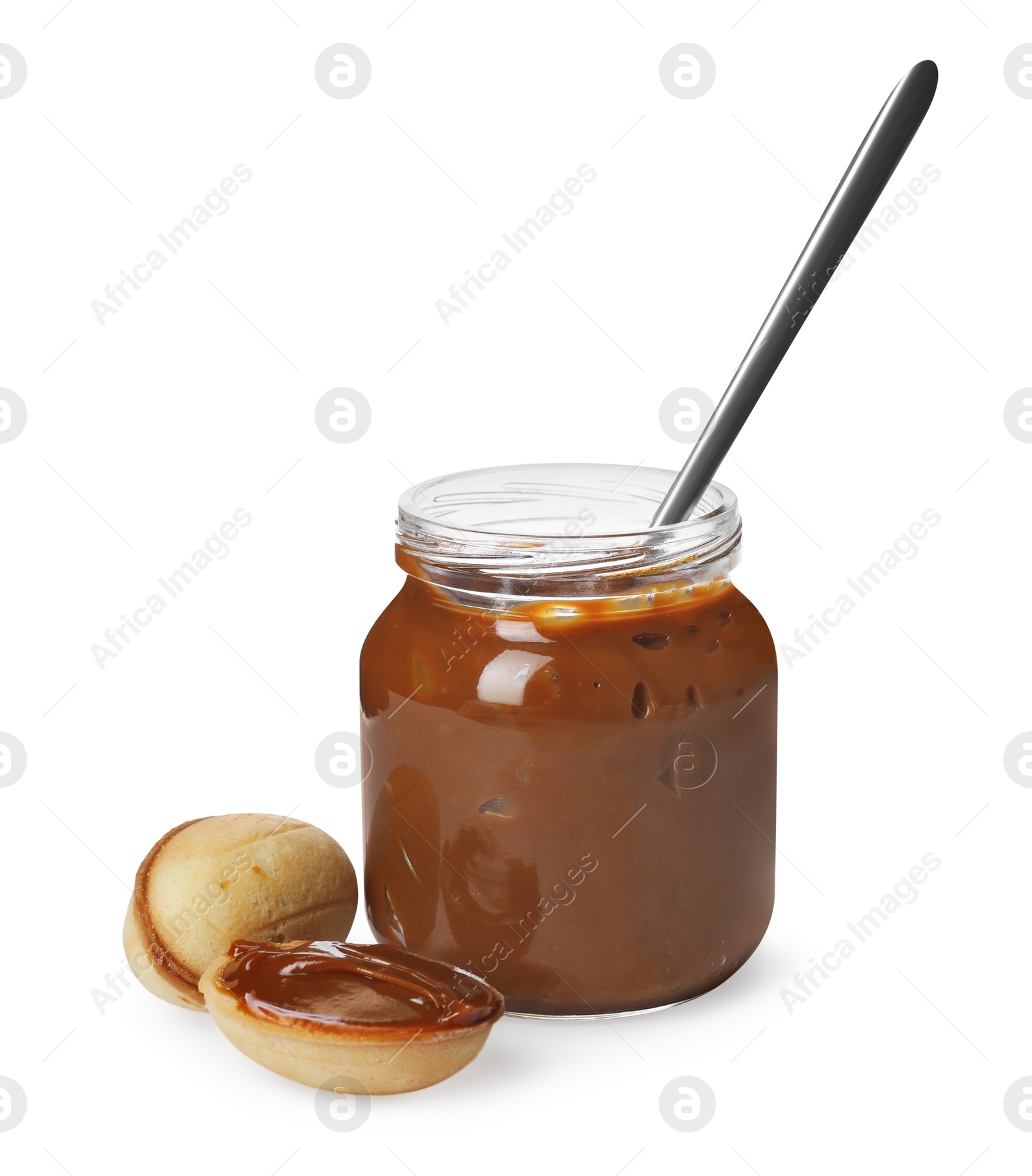 Photo of Jar with boiled condensed milk, spoon and walnut shaped cookies on white background