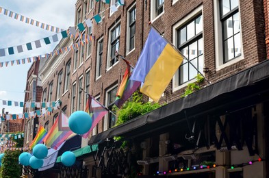 Picturesque view of city street with rainbow and Ukrainian flags