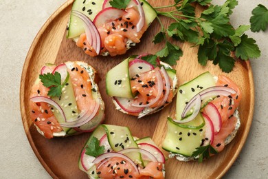 Tasty canapes with salmon served on light grey table, top view