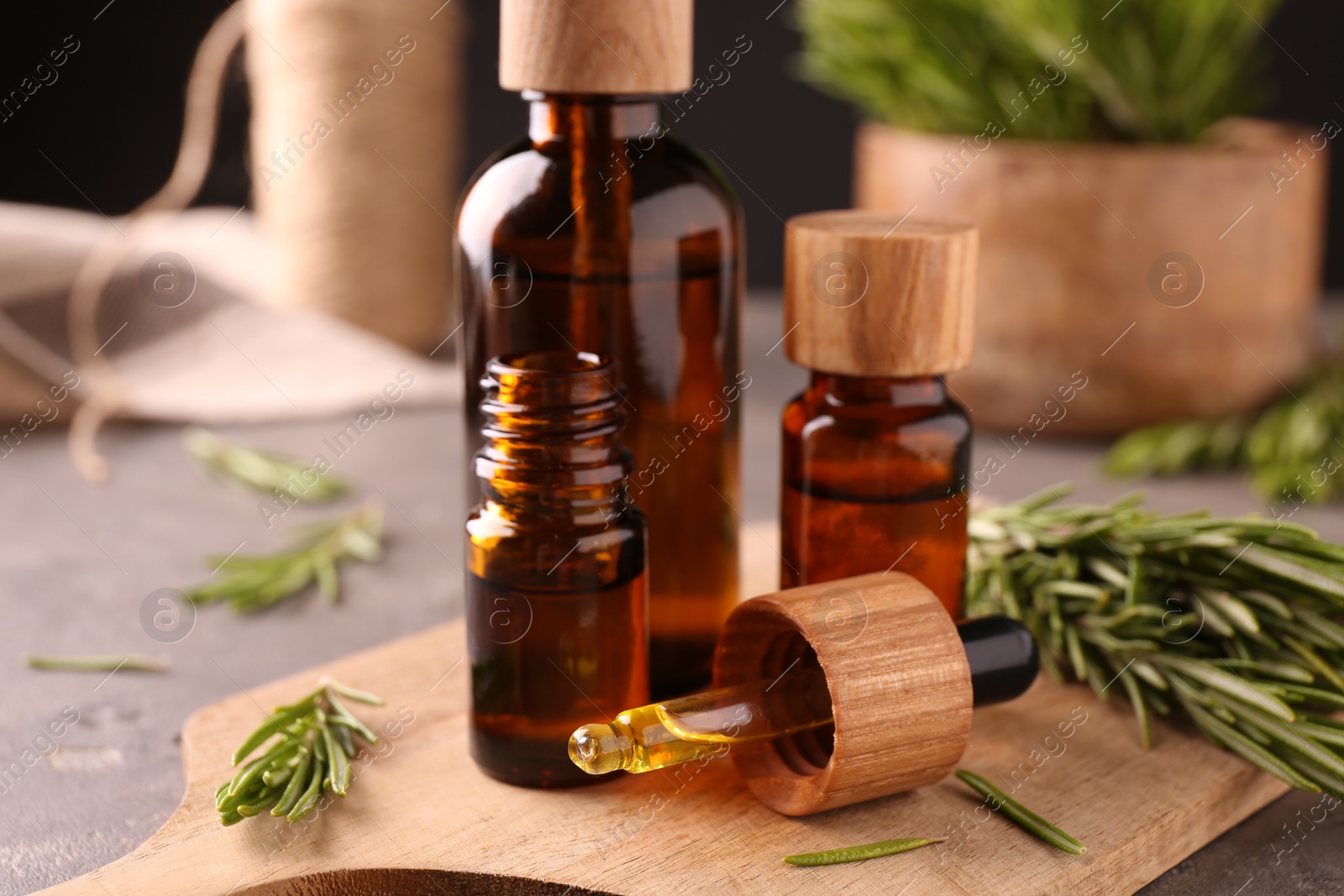 Photo of Essential oil in bottles, dropper and rosemary on table, closeup