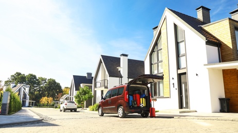 Photo of Car with suitcases in trunk near modern house outdoors. Moving day