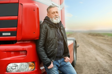 Photo of Portrait of mature driver at modern truck outdoors. Space for text