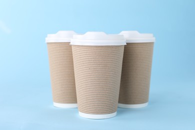 Photo of Paper cups with white lids on light blue background. Coffee to go