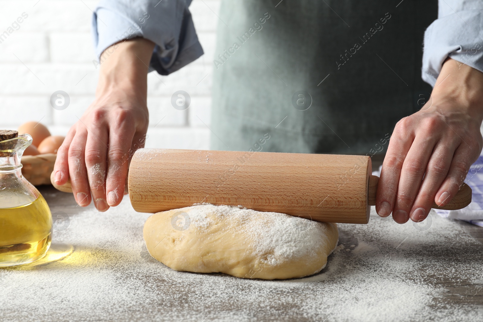 Photo of Woman rolling raw dough at table, closeup