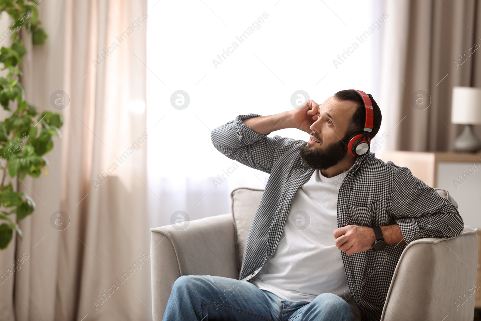 Photo of Mature man with headphones resting in armchair at home