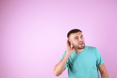 Young man with hearing problem on color background with copy space text