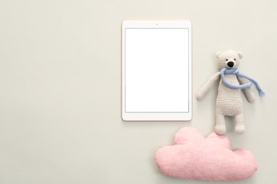 Photo of Modern tablet, toy cloud and bear on light background, flat lay. Space for text