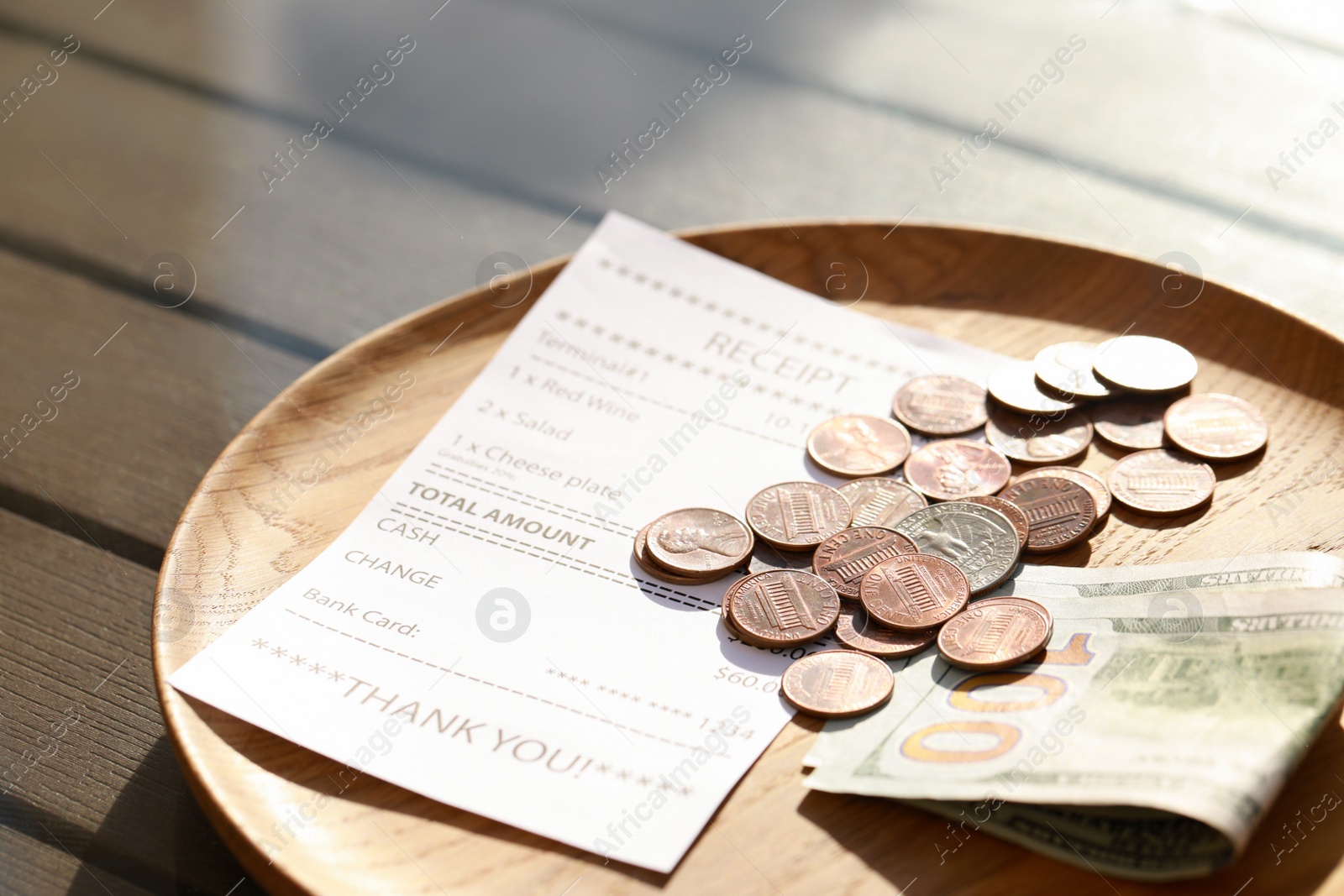 Photo of Wooden plate with payment for order and receipt on table, closeup. Leave tip