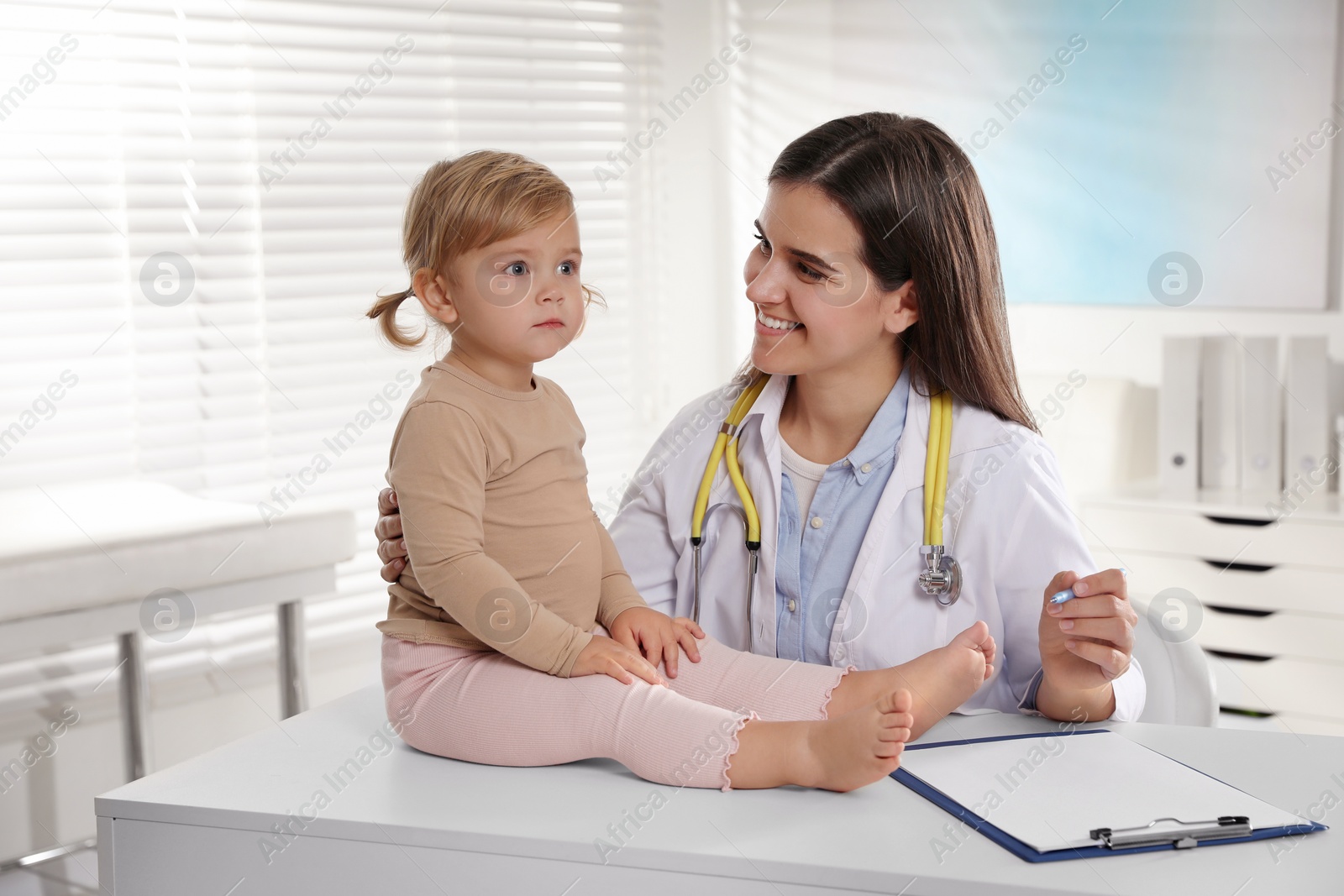 Photo of Pediatrician examining cute little baby in clinic