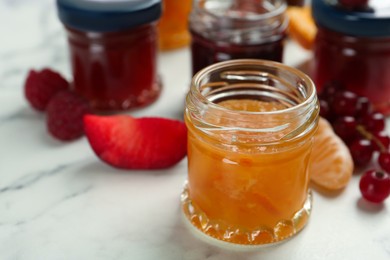 Photo of Jar of sweet jam on white marble table, closeup. Space for text