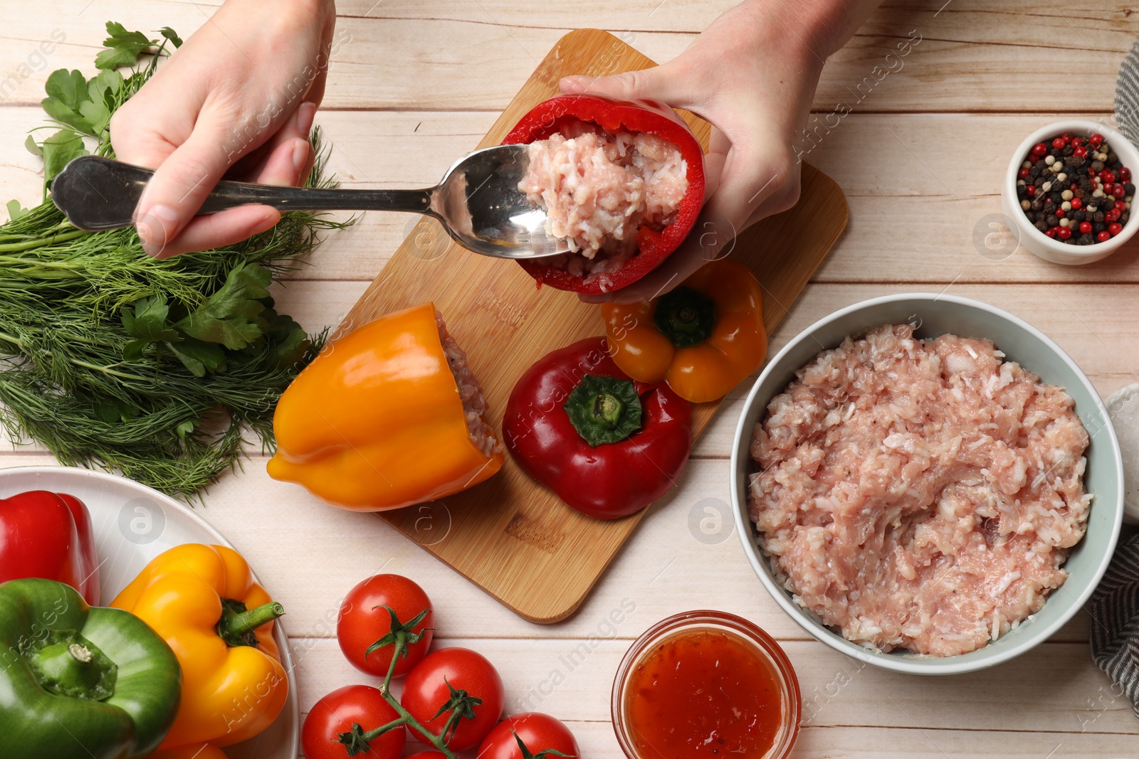 Photo of Woman making stuffed peppers with ground meat at white wooden table, top view