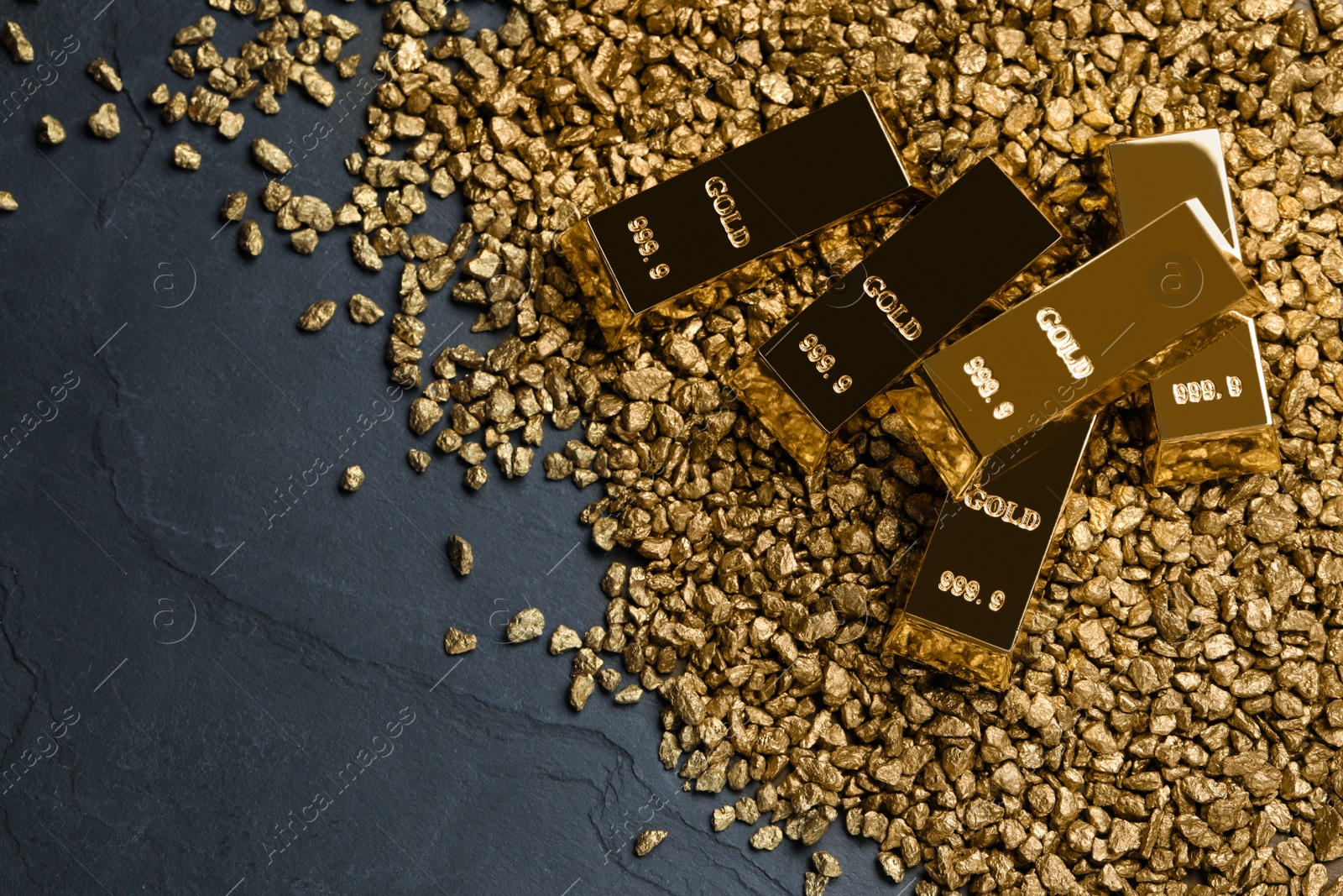 Photo of Gold nuggets and ingots on black table, flat lay. Space for text