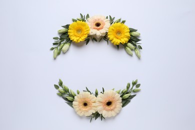 Wreathes made of beautiful flowers and green leaves on light background, flat lay. Space for text