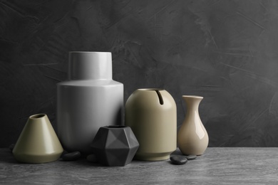 Photo of Stylish empty ceramic vases and rocks on grey table