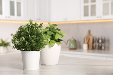 Artificial potted herbs on white marble table in kitchen, space for text. Home decor