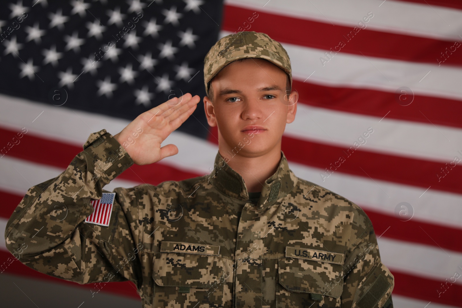 Photo of Male soldier saluting against American flag. Military service