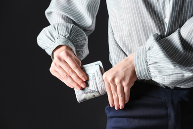 Photo of Woman putting bribe into pocket on black background, closeup