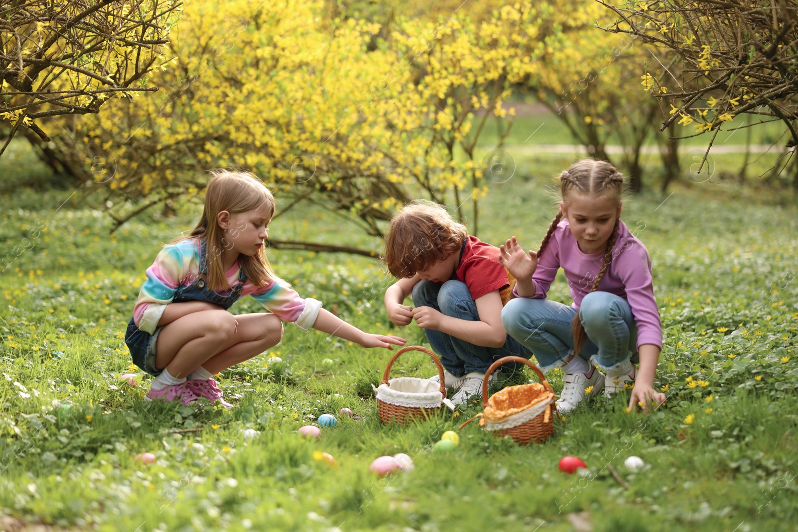 Photo of Easter celebration. Cute little children hunting eggs outdoors