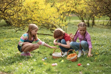 Photo of Easter celebration. Cute little children hunting eggs outdoors