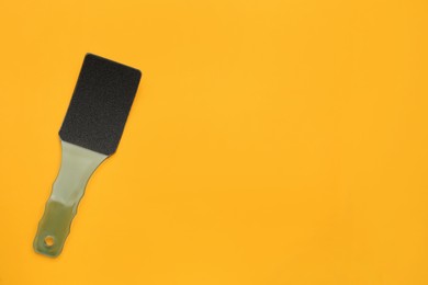 Photo of Foot file on orange background, top view with space for text. Pedicure tool