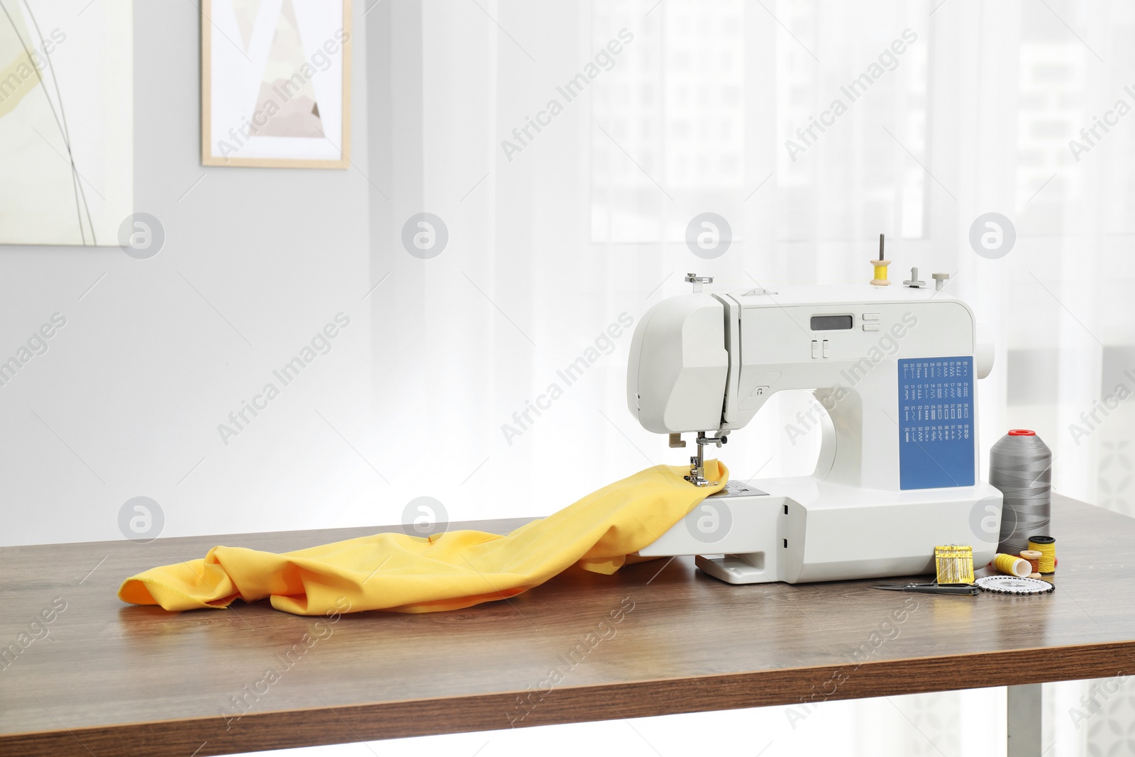 Photo of Sewing machine with fabric and craft accessories on wooden table indoors